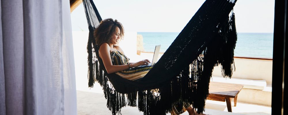 Woman relaxing in hammock in front of beach scene
